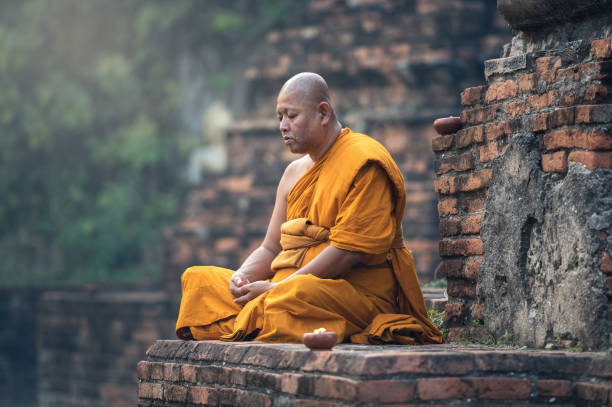 Buddhist monk meditating at a temple wearing an orange robe